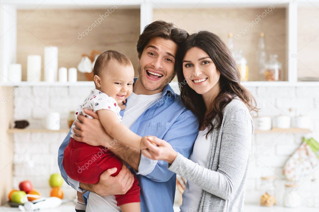 Cheerful mother, father and baby at kitchen interior