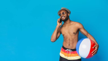 Şişme top tutan ve cep telefonundan konuşan Afrikalı-Amerikalı adam