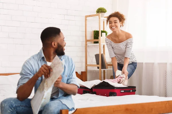 Mujer haciendo las maletas y el hombre estudiando mapa — Foto de Stock