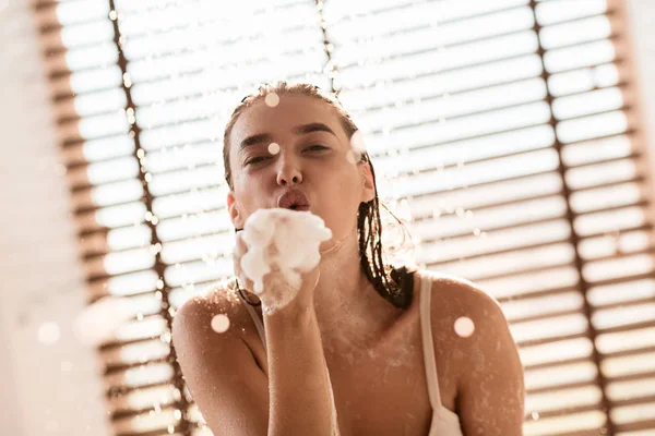 Lány fúj szappanbuborékok, figyelembe zuhany otthon — Stock Fotó
