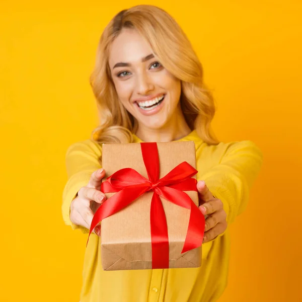 GIrl Stretching Gift Box per fotocamera su sfondo giallo — Foto Stock