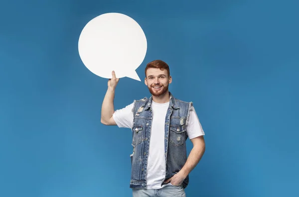 Jovem masculino segurando bolha de fala em uma mão e sorrindo — Fotografia de Stock