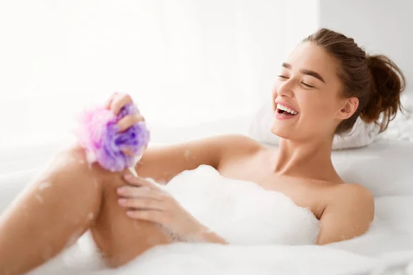 泡風呂でスポンジで足を洗う女性 — ストック写真