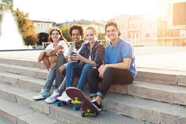 Teen friends company sitting outdoor, spending summer together