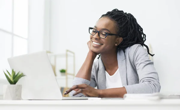 Афроамериканка смотрит на экран ноутбука в офисе — стоковое фото
