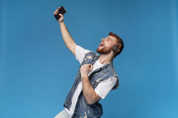 Handsome guy singing from the soul in headphones on background — Stock Photo, Image