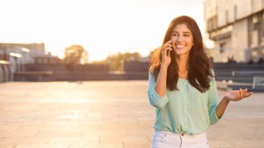 Kadın yönetici telefonda konuşuyor, şehirde yürüyor
