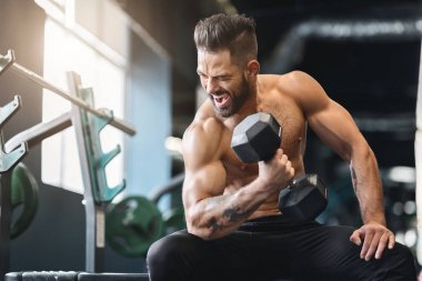Çıplak vücut geliştirmeci spor salonunda dumbbell ile egzersiz