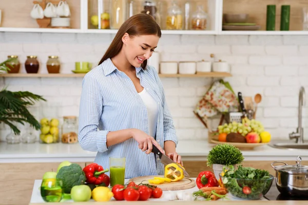 Diätkonzept. glückliche Frau schneidet Paprika in Küche — Stockfoto
