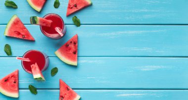 Karpuz suyu ve mavi ahşap arka plan üzerinde dilimler
