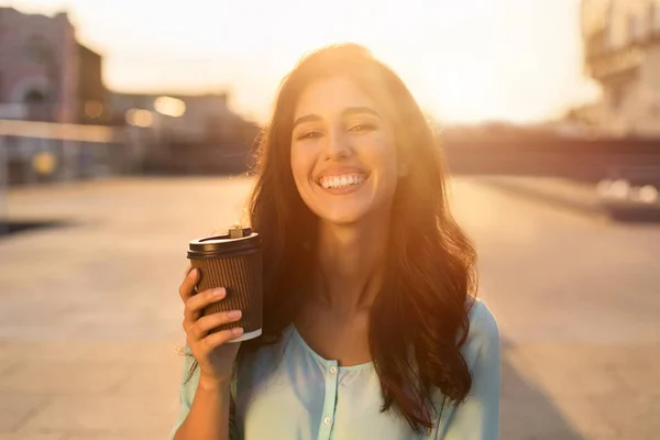 Mujer feliz caminando por la calle de la ciudad con café para llevar — Foto de Stock