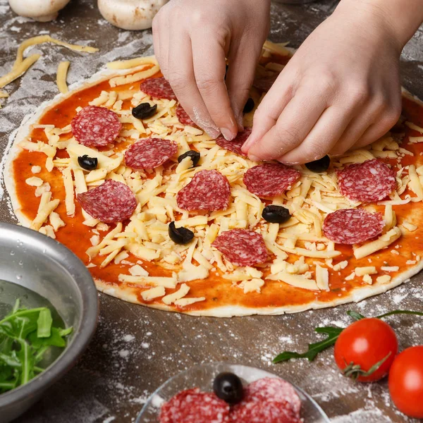 Woman Adding Salami To Pizza, Decorating With Various Ingredients