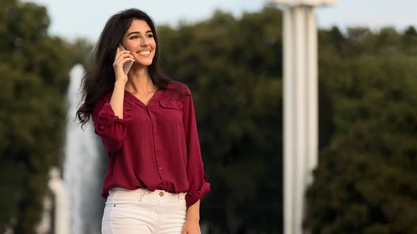 Businesswoman having phone talk, walking in the city during break