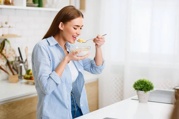 Kvinna äter majsflingor äta frukost i köket — Stockfoto