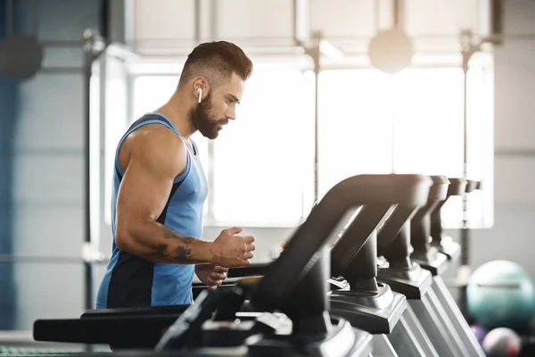 Sportieve man draait op loopband bij Gym interieur — Stockfoto