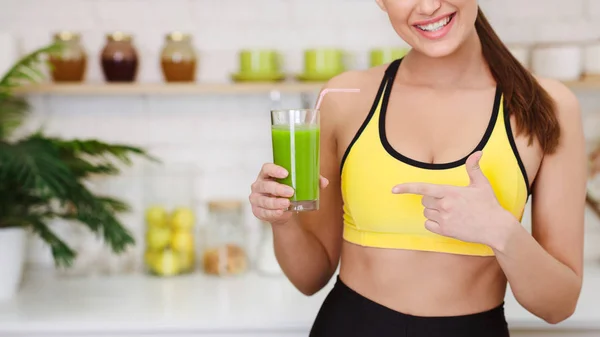 Sportliche Frau zeigt auf Detox-Smoothie in Küche — Stockfoto