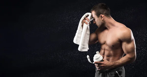 Jovem desportista limpando seu suor após o treinamento duro e segurando água — Fotografia de Stock