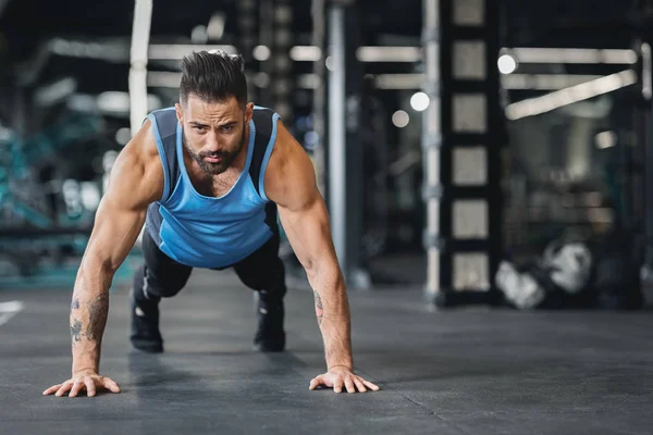 Skoncentrowany muskularny facet robi push up ćwiczenia — Zdjęcie stockowe