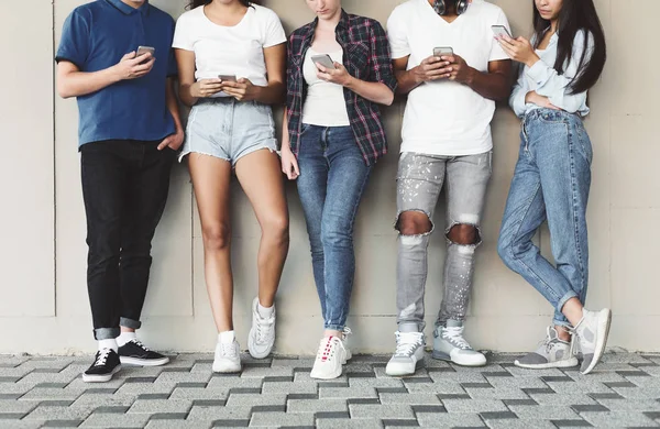 Açık havada cep telefonu kullanan çeşitli gençlerin grubu