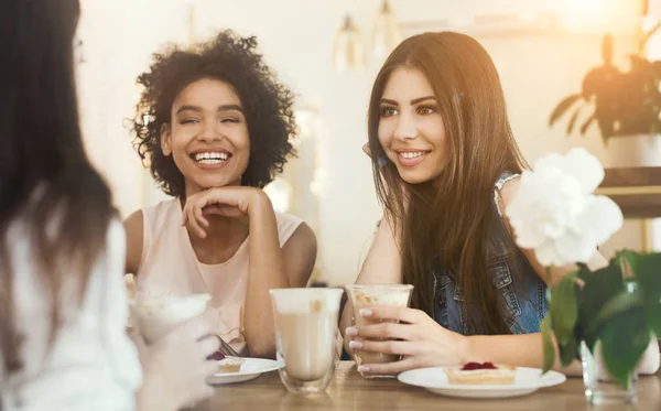 Young funny girls sitting in cafe, drinking coffee and talking — Stock Photo, Image