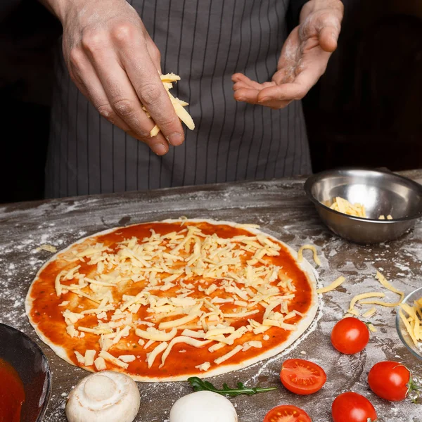 Italienische Küche. Koch gibt geriebenen Käse zur Pizza — Stockfoto