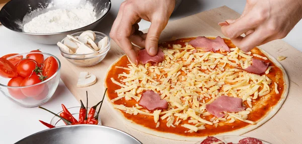 Mann legt Schinken auf Pizza in Pizzeria — Stockfoto