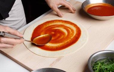 İtalyan pizza hazırlık. Şef temel pizza sosu ekleme