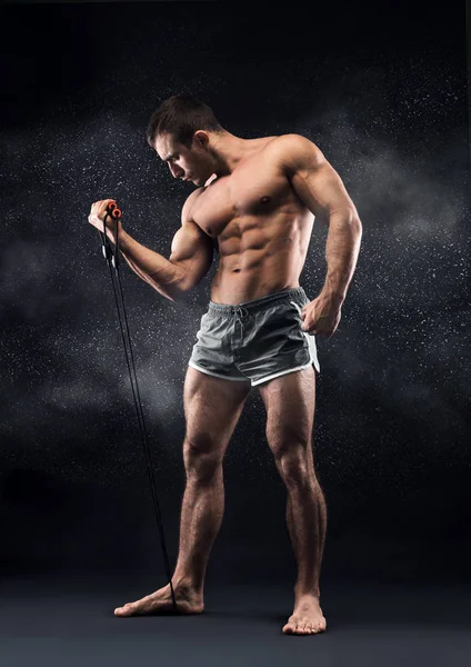 Serious joven deportista bombeando sus músculos de la mano con elástico — Foto de Stock