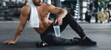 Çıplak adam su şişesi tutan, spor salonunda katta oturan
