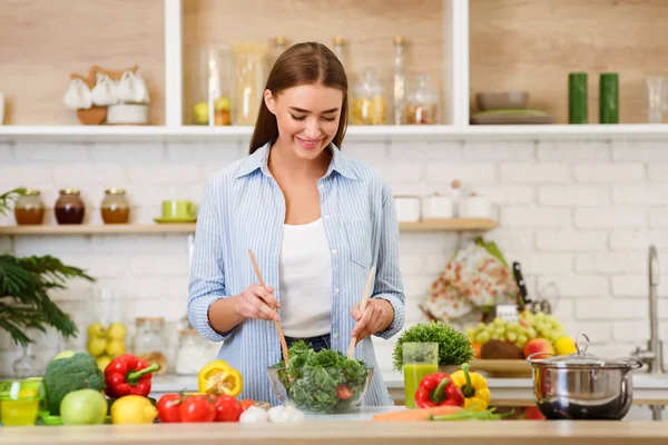 Здоровое питание. Женщина смешивает свежий салат на кухне — стоковое фото