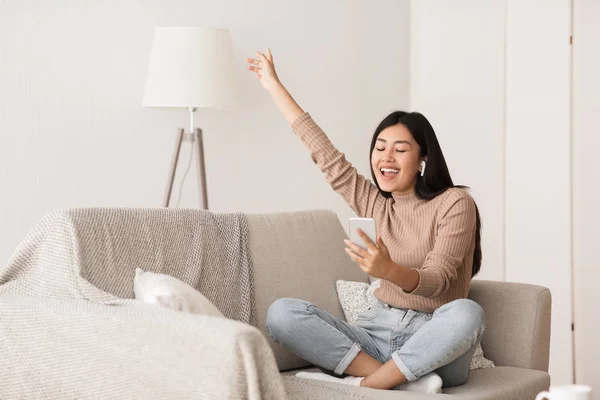 Glückliche Mädchen genießen Musik in Airpods, entspannen auf dem Sofa — Stockfoto
