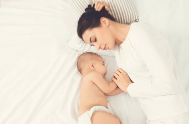 Genç Anne ve yatakta uyuyan sevimli bebek