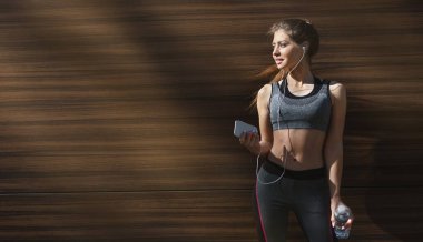 Sportif kız gölgede rahatlatıcı ve müzik dinliyor