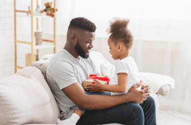 Hediye kutusu ile küçük kızı ile oturan Afrikalı Amerikalı adam