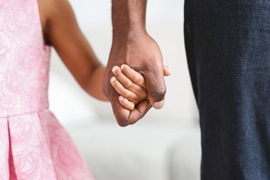 Siyah baba küçük kızını nazikçe elinden alıyor.