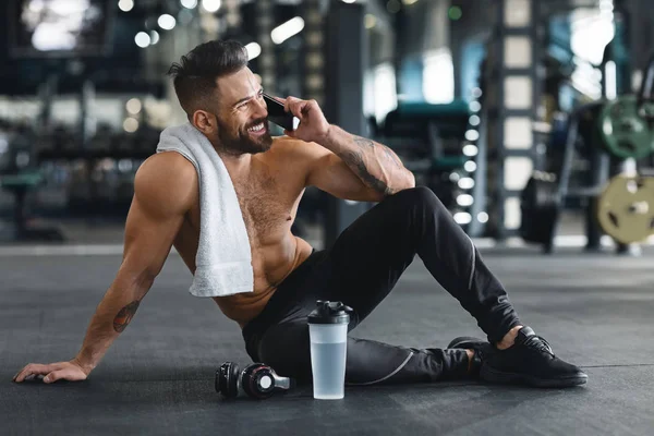 Muscular cara falando no celular depois de treinar no ginásio — Fotografia de Stock