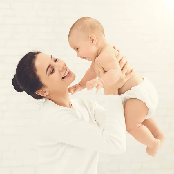 Fiatal anyuka tartja a boldog baba, levegőben — Stock Fotó
