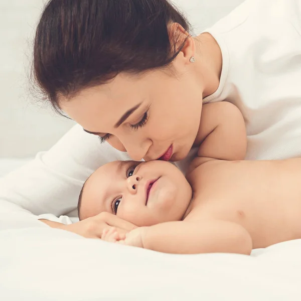 Matka całuje jej słodkie adorable baby w łóżku — Zdjęcie stockowe