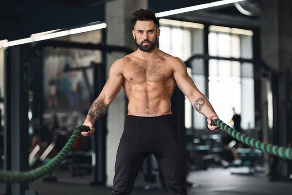 Muscular cara com torso nu exercitando com cordas de batalha — Fotografia de Stock