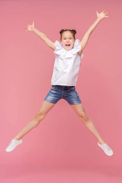 Lustiges kleines Mädchen lacht und springt auf rosa Hintergrund — Stockfoto