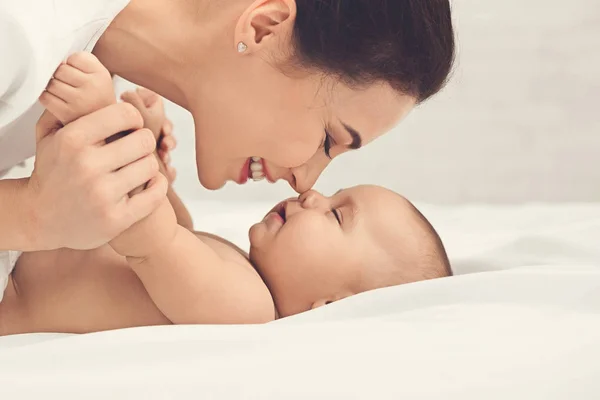 Mor och barn röra näsor i sängen — Stockfoto