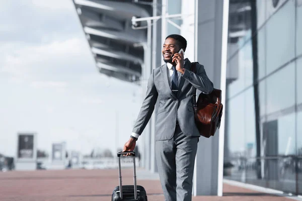 Homem africano andando com bagagem e conversando no telefone — Fotografia de Stock