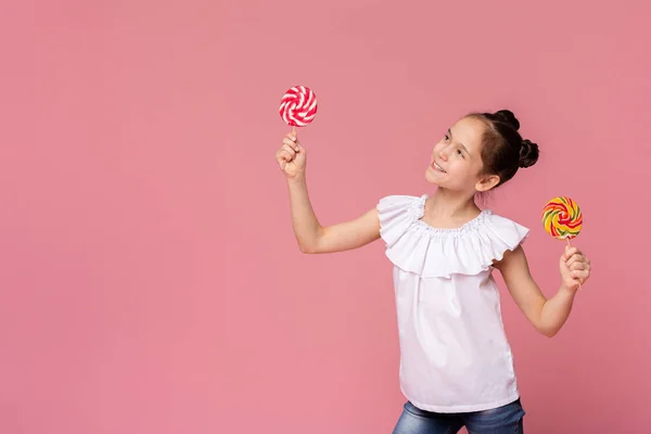 Nettes kleines Mädchen schaut mit großen bunten Lutschern in den leeren Raum — Stockfoto