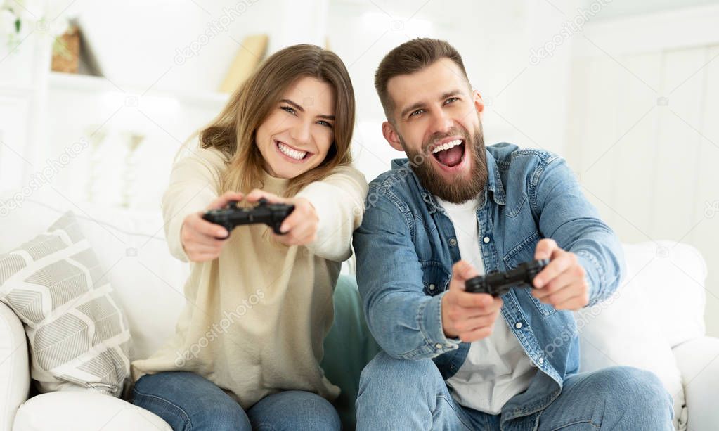 Laughing Couple Playing Video Games By Joysticks