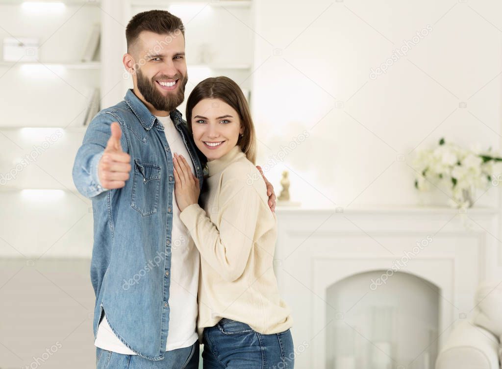 Couple Hugging In New Apartment, Man Showing Thumb Up