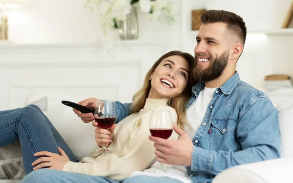 Glückliches Paar, das Wein trinkt und zu Hause fernsieht — Stockfoto