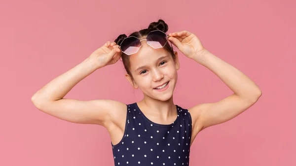 Adorável menina vestindo óculos de sol elegantes em rosa — Fotografia de Stock