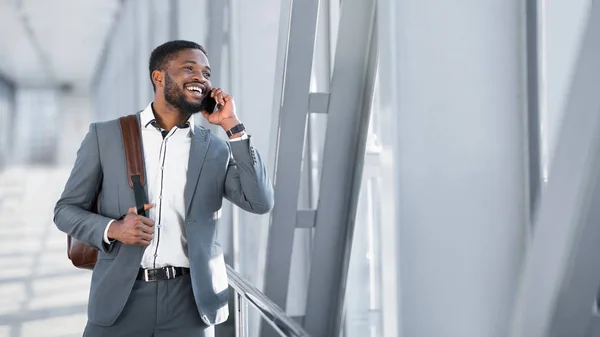 Homme d'affaires africain marchant à l'intérieur de l'aéroport et parlant au téléphone — Photo
