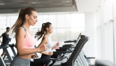 Spor salonunda eğitim. Kadın koşu bandı üzerinde kardiyo egzersiz yapıyor