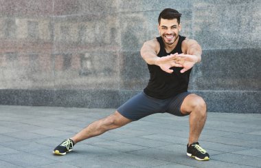Genç kaslı adam germe egzersizleri açık yapıyor